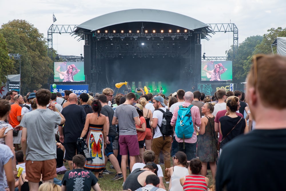Large crowd of people standing in front of a stage at an outdoor concert. Paris, France.