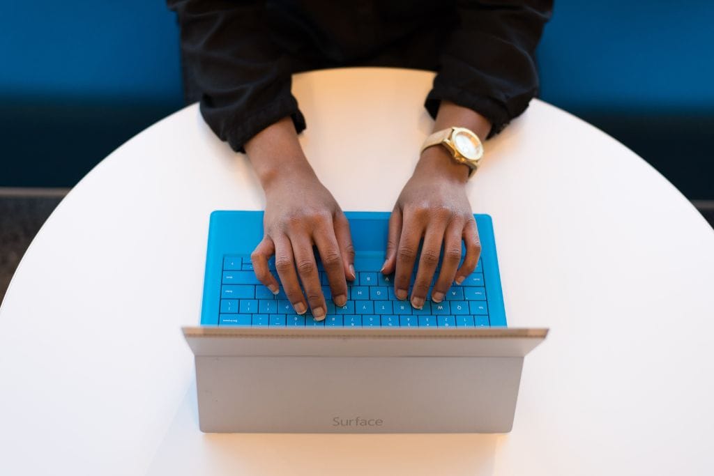 A photo of two hands typing on a Mac laptop.