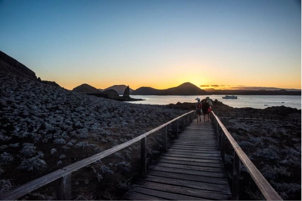 A couple walking toward the sunset in the Galapagos. You can choose from many luxury tours like, the Galapagos Islands Cruise: 5-Day Eastern Itinerary aboard Yacht La Pinta.