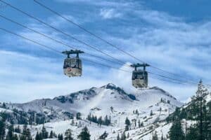 Two Gondolas in the air over a snowy landscape.