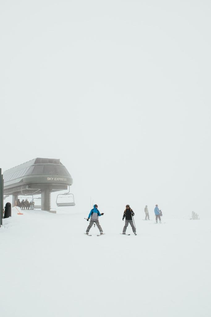 Skiers getting off a chair lift in very snowy conditions in Lake Tahoe, California. 