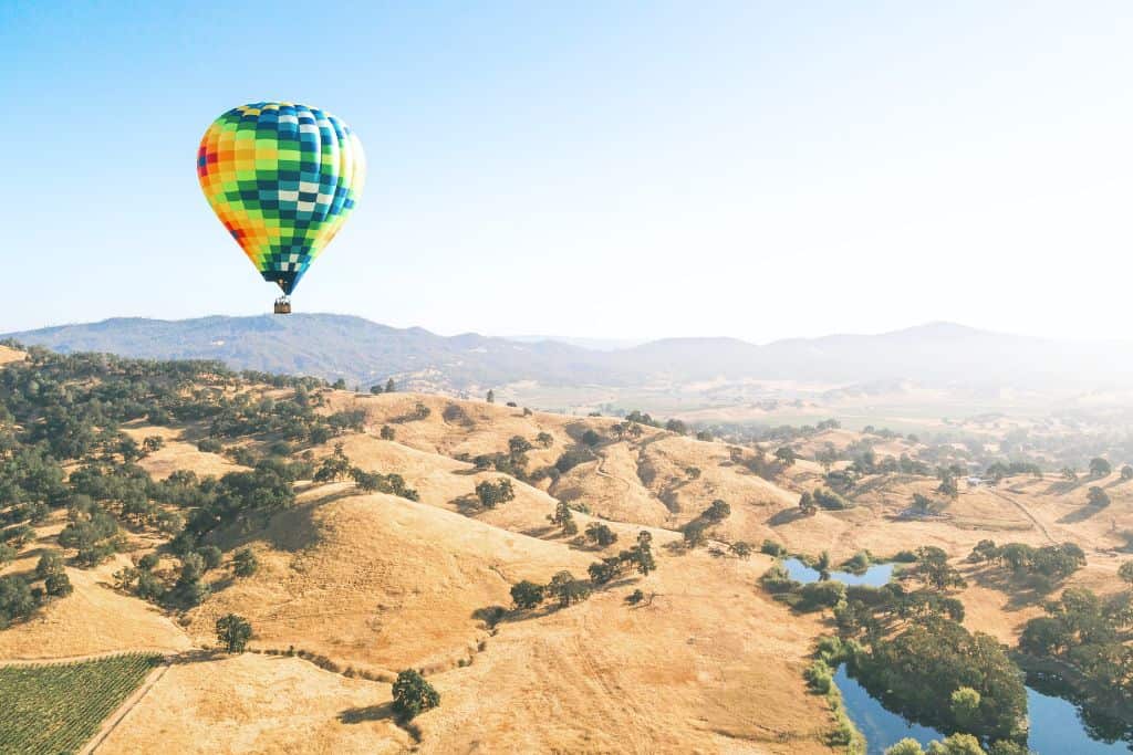 One hot air balloon over a valley and a body of watering Temecula, California.