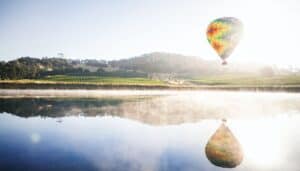A hot air balloon over vineyards and a lake in Temecula, California.