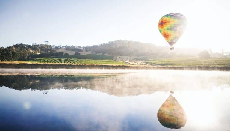 A hot air balloon over vineyards and a lake in Temecula, California.