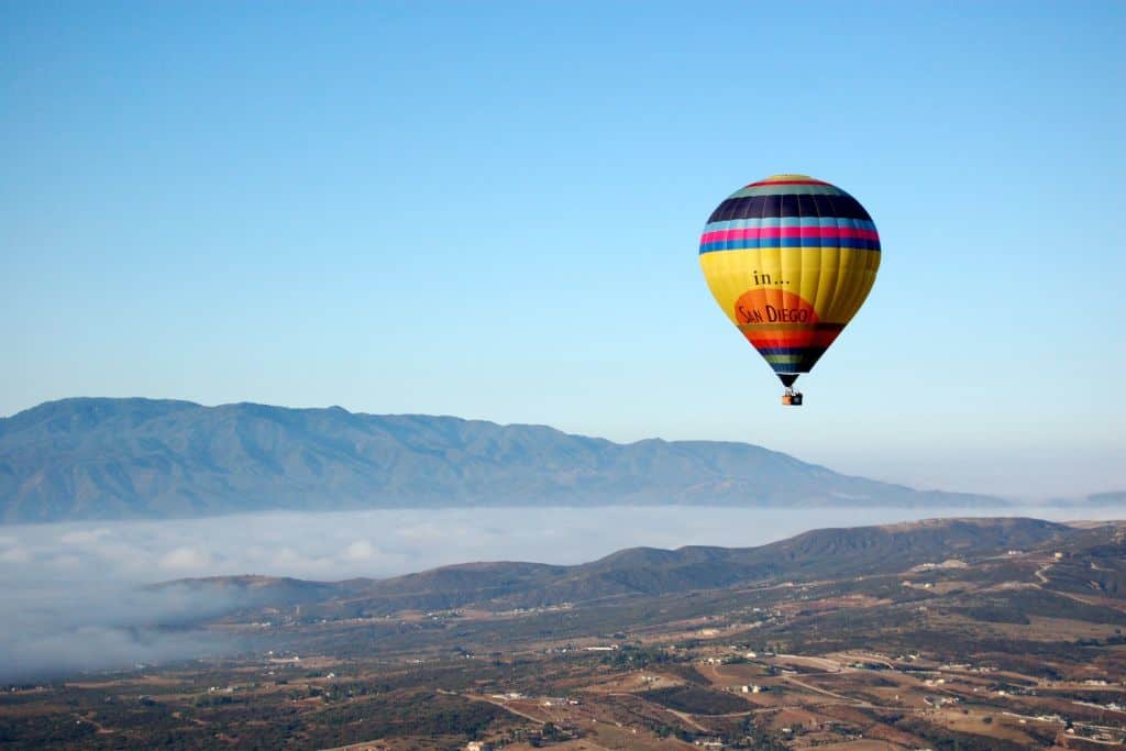 A hot air balloon over mountains and fog.