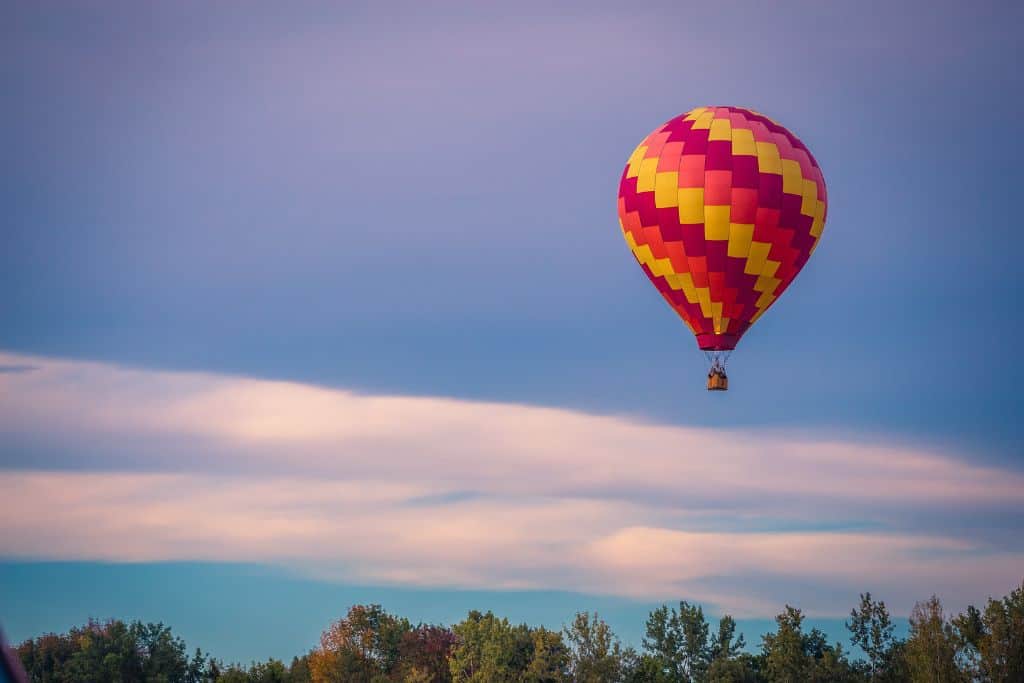 An orange, yellow, and red hot air balloon in a purplish sky.