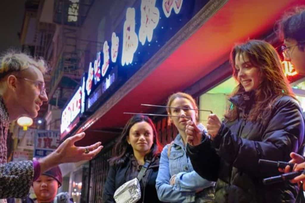 A group of people standing on the street at night.