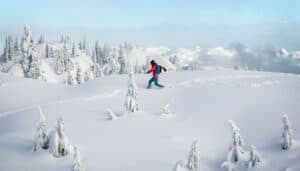 A man alone trekking across a very snowy mountain.