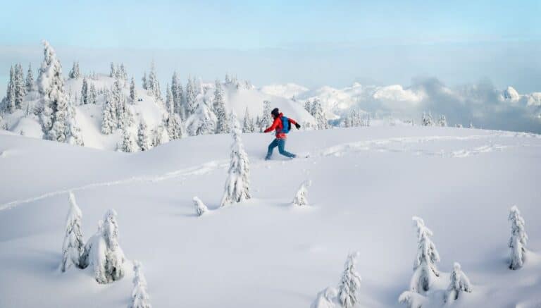 A man alone trekking across a very snowy mountain.