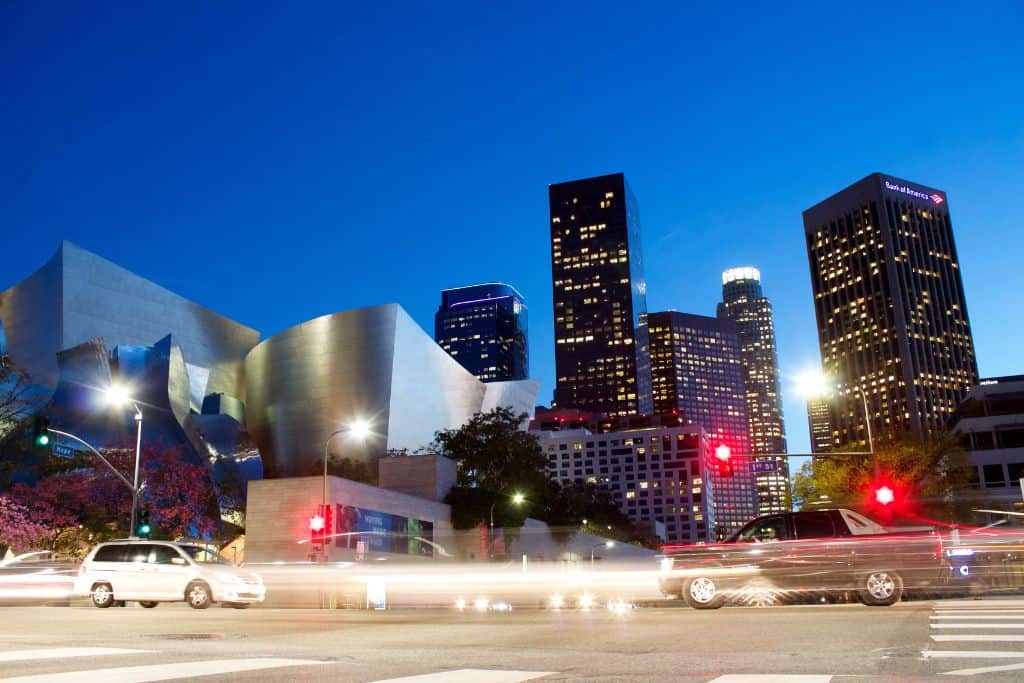 The Walt Disney Concert Hall Building and tall buildings in LA surround it at night.