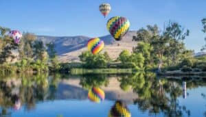 Four hot air balloon flying over a lake in Temecula, with their reflections on the lake.