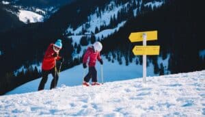 A woman and a child on ski walking up hill.