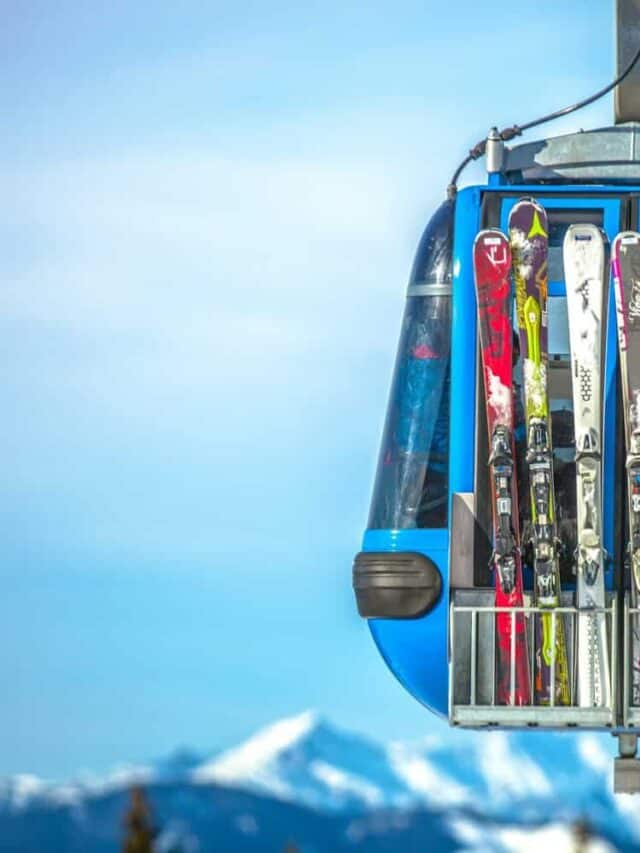 A gondola with five pairs of skies strapped to it.