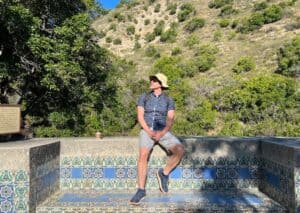 A hot man sitting on a beautifully tiled bench looking up at the scenery.