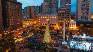 An aerial view of Union Square in San Francisco at night with a big Christmas tree lit up in the center.