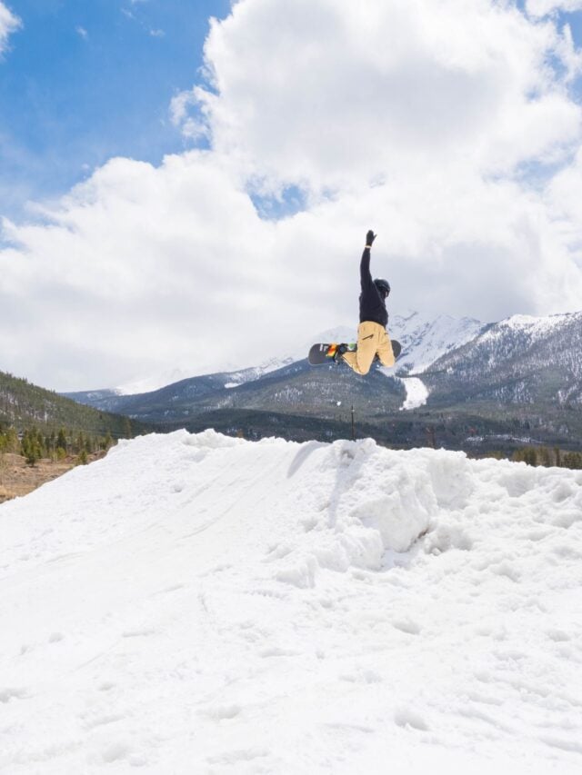 A snow boarder lifting off a pile of snow.