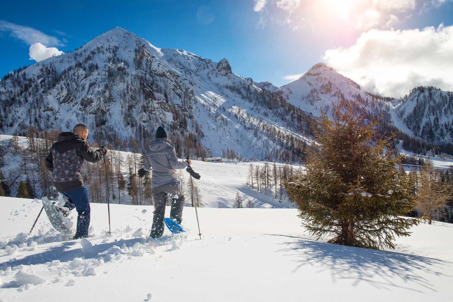 Two people treking through the snow on snow shoes.