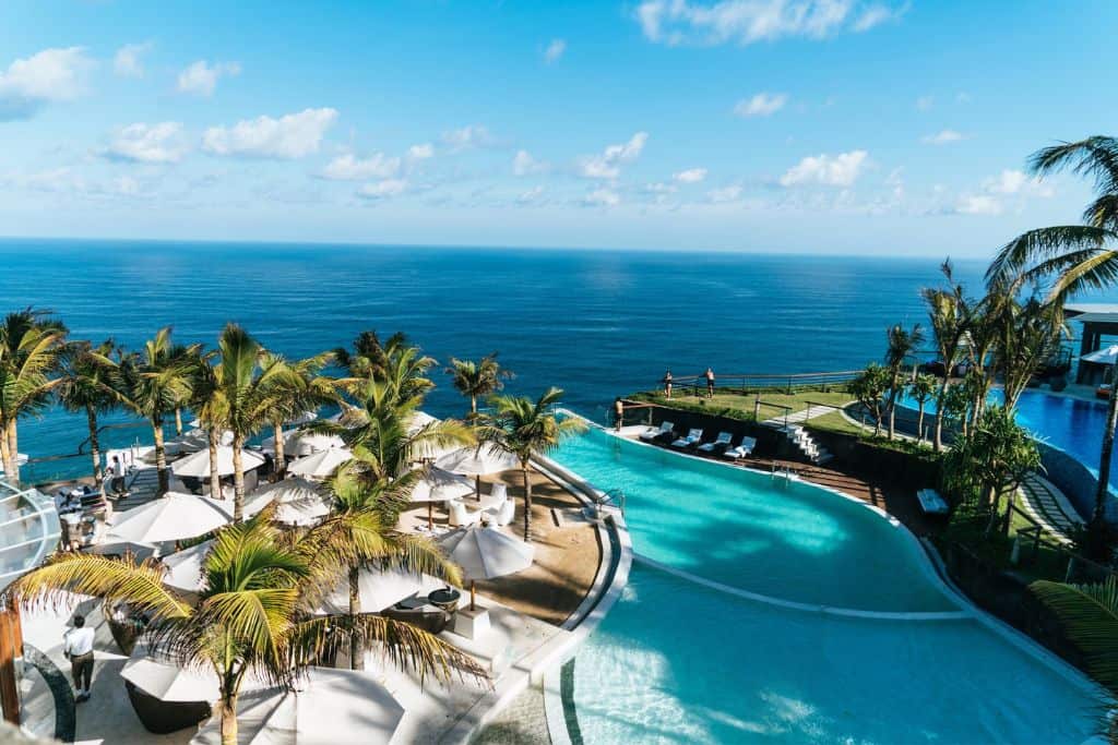 A pool with palm trees going toward the ocean.
