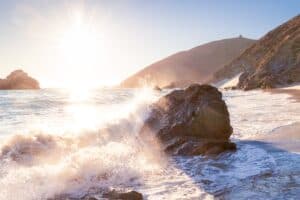Rough sea water in Big Sur crashing against a large rock.