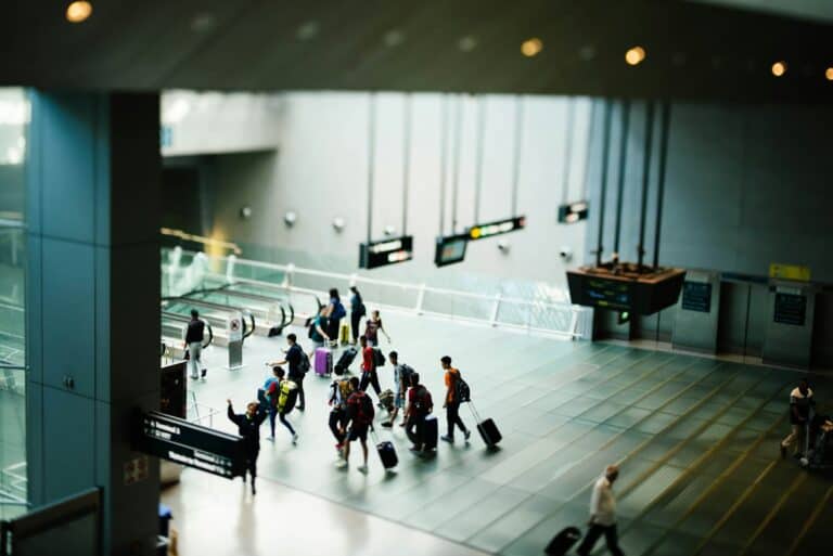 People scurrying in an airport while pulling suitcases.