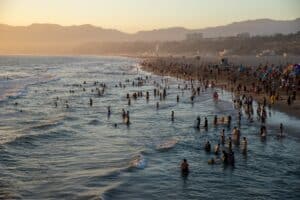 Santa Monica beach in the summer with people swimming and wading in the waters off the beach. Santa Monica, California.