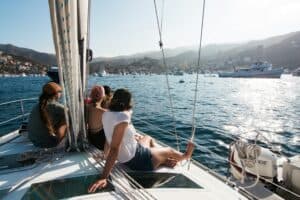 Four people sitting on a sailboat looking at the water.